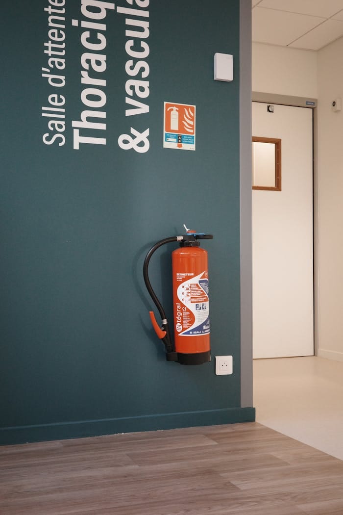 Red fire extinguisher in a hospital waiting room with safety instructions visible.